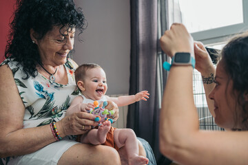 Grandmother, mother and baby girl playing together at home. Grandmother and mother playing with a...