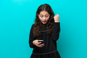 Fototapeta premium Little girl isolated on blue background surprised and sending a message