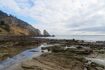 Fototapeta premium Falaise et formation rocheuse sur une plage de la presqu'île de Crozon à marée basse, en Bretagne.