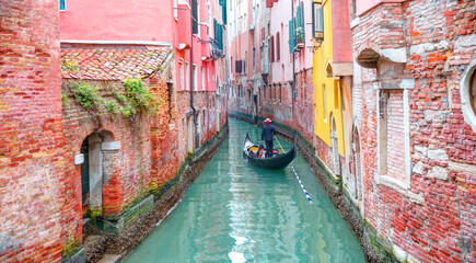 Venetian gondolier punting gondola through green canal waters of Venice Italy © muratart