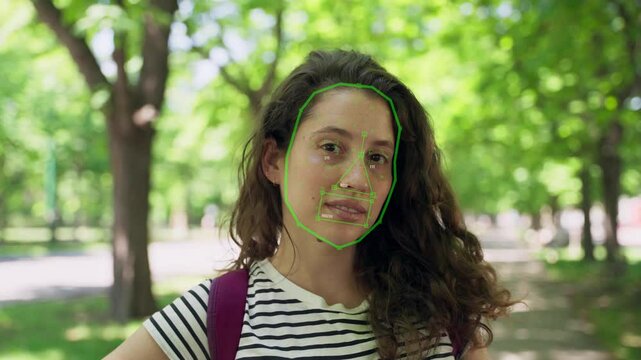 Young woman face detection feature recognition with artificial intelligence ai. Female in park has her face scanned and read with biometric technology and special facial id tools and algorithm 