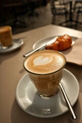 Desayuno o merienda compuesta de café con leche con forma de corazón y croissant