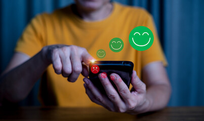 Close up woman hand holding smart phone  and touch  the unhappy  face emoticon on the virtual touch screen, to give rating of products and service, Customer service and business satisfaction survey.