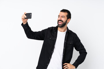 Young man with beard over isolated white background making a selfie