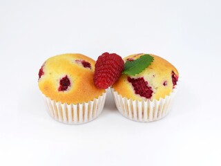 Muffins with raspberries on white background with fresh fruit, decorated with melissa leaf