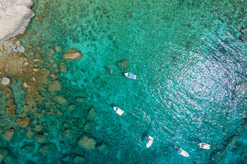Aerial view on clear turquoise blue water with speed boats on small Kastelli beach on Corfu island.