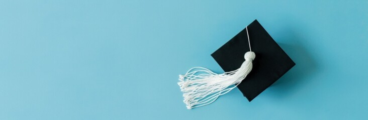 Graduation cap with white tassel on blue background, educational achievement and success concept