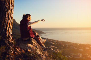 Couple, rock and outdoor with relax on peak or point for view, adventure and bonding in nature or environment. Man, woman and pointing on mountain for fresh air, peace and horizon with love on trip.