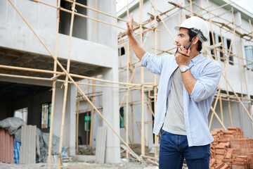 worker or architect using walkie talkie and talking to someone at construction site