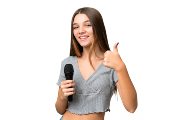Teenager singer girl picking up a microphone over isolated background with thumbs up because something good has happened