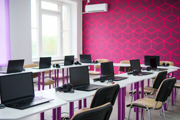 School desks with laptops in an empty modern classroom