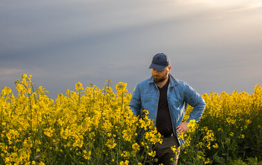 Young farmer in field of blooming rapeseed