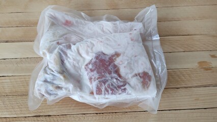 Piece of frozen pork lard in a vacuum packaging on the wooden background