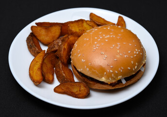 Hamburgers and homemade potatoes on a white plate. Delicious breakfast. Fast food.