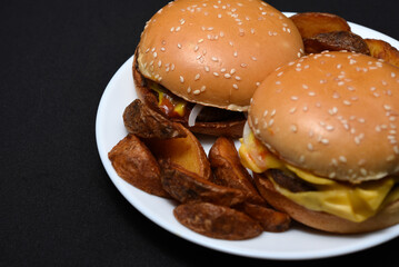 Hamburgers and homemade potatoes on a white plate. Delicious breakfast. Fast food.
