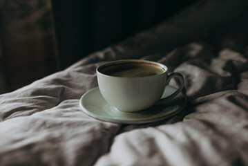 White coffee cup on the bed in morning bedroom, mock up. Lifestyle morning routine.