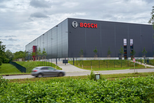 Modern BOSCH building, car passing by in the foreground, surrounded by greenery, depicting corporate architecture and motion. Wernau, Germany, Europe.