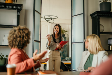 A young female candidate walks into a office, holding a CV, ready to have a job interview with an HR team