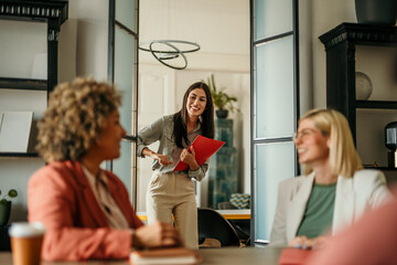 Two businesswomen welcoming and greeting new job candidate in a bright office