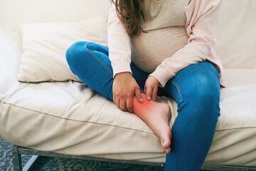 Foot, pain and hands of pregnant woman on sofa with inflammation glow, joint or bone, burnout or risk at home. Injury, red and girl person with swollen ankle, discomfort or pregnancy fatigue in house