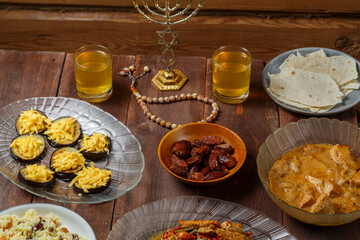 Shabbat table with traditional holiday food meat and sweets menorah. Horizontal photo.