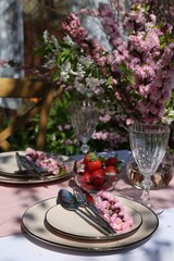 Stylish table setting with beautiful spring flowers in garden