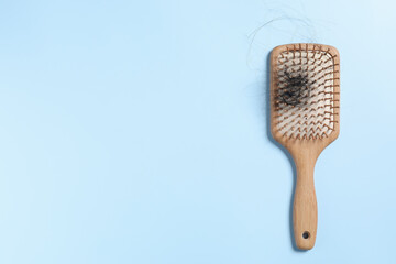 Wooden brush with lost hair on light blue background, top view. Space for text