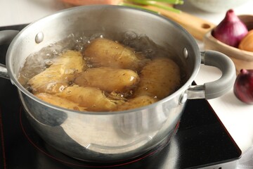 Boiling potatoes in metal pot on stove, closeup