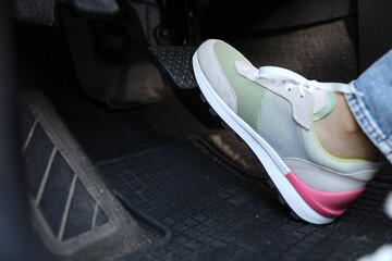 Woman pushing on pedal of car brake, closeup