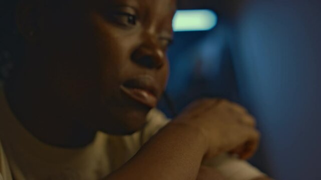 Side closeup of African American woman having intrusive thoughts about past traumatic events and staying awake at home at night, looking depressed and helpless