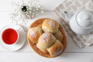 Delicious dough balls with powdered sugar in basket, tea, teapot and gypsophila flowers on white...