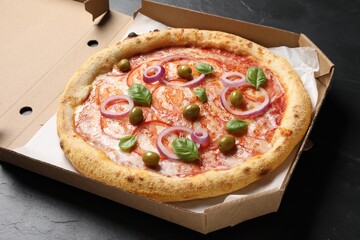 Delicious vegetarian pizza in box on black table, closeup