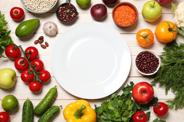 Different vegetarian products and plate on light wooden table, top view
