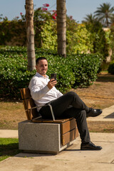 Hombre joven con traje y camisa en sitio lujoso con mar.  Business man. Trabajando con tablet y...