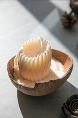 Decorative candle at home on the table in a coconut shell
