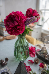 Large red peonies in a vase on the table at home