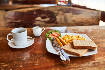 Empty, breakfast and coffee on table in home with eggs for nutrition, protein or healthy dish in morning. Weekend, toast and knife with fork for eating food, hospitality and room service at lodge