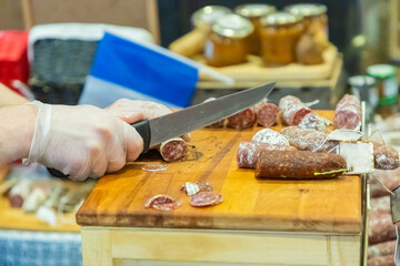 unrecognizable female hands cut a piece of salami