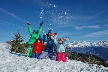 Family have fun together in mountains, throw snow up