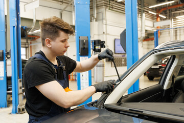 Young technician preparing a car for the installation of a rear windshield