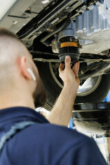 A mechanic at a car service center changes the oil filter in a car