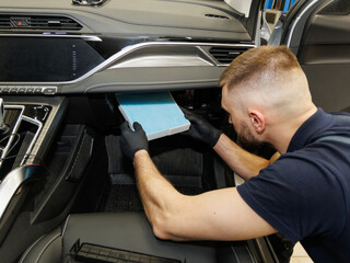 a mechanic at a car service center changes the cabin filter