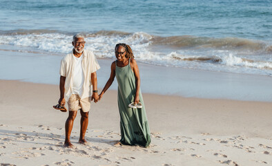 Elderly black couple enjoying a walk on the beach