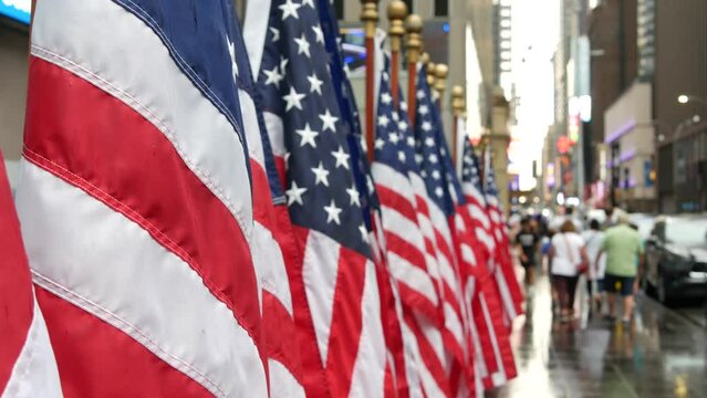 New York, row of american flags. Manhattan midtown near Broadway Times Square, Rockefeller subway. People on 48th city street . Symbol of freedom, democracy, liberty and patriotism. Rainy 11 September