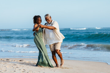 Senior African American couple dancing on the beach at sunset