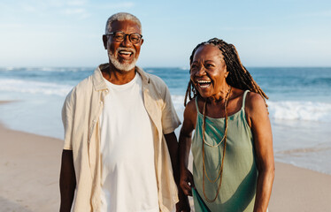 Cheerful elderly African American couple walking on the beach