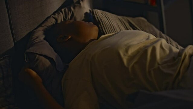 Side shot of unhappy traumatized Black woman turning over in bed and waking up at night, having nightmares about past events. Living with post-traumatic stress disorder and sleepless nights