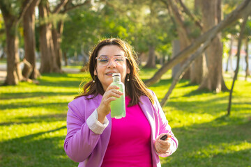 Fototapeta premium Stylish Woman in a Park Enjoying a Drink