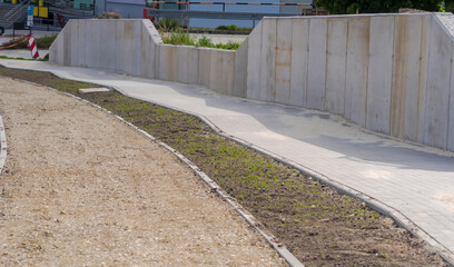 Chodnik z murem oporowym i ścieżką rowerową przygotowaną do asfaltowania. Nowo wybudowana droga w mieście - droga już na ukończeniu.