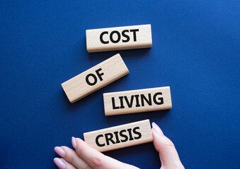Cost of Living Crisis symbol. Wooden blocks with words Cost of Living Crisis. Businessman hand. Beautiful deep blue background. Business and Cost of Living Crisis. Copy space.